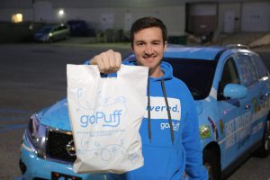 a GoPuff delivery driver holding up a bag of goods