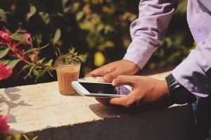 A Comprehensive Guide to the HomeAway App for Travelers: Man holding iPhone while sitting outside with a beverage