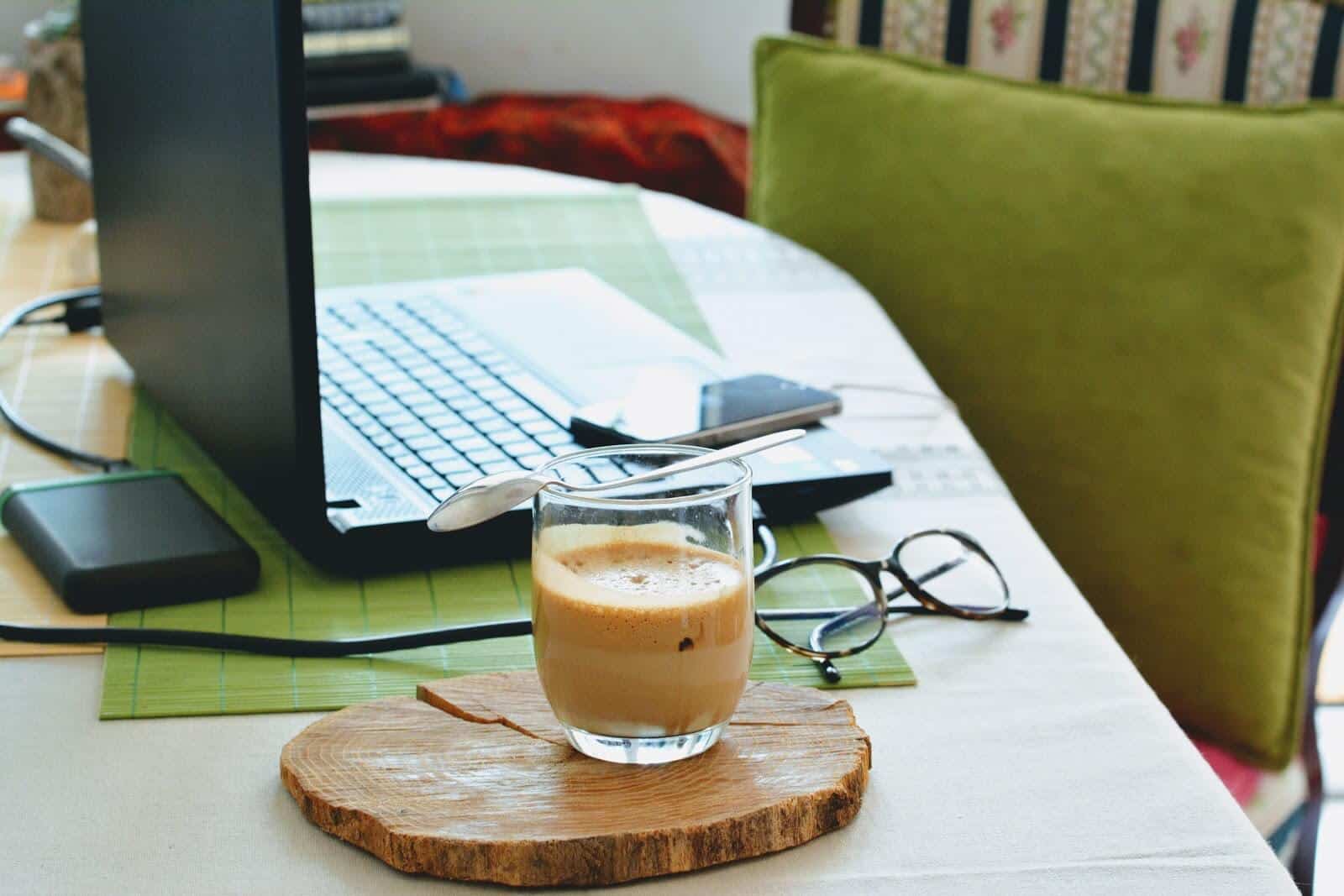 Legitimate work at home jobs: Setup of laptop, phone, coffee, and eyeglasses