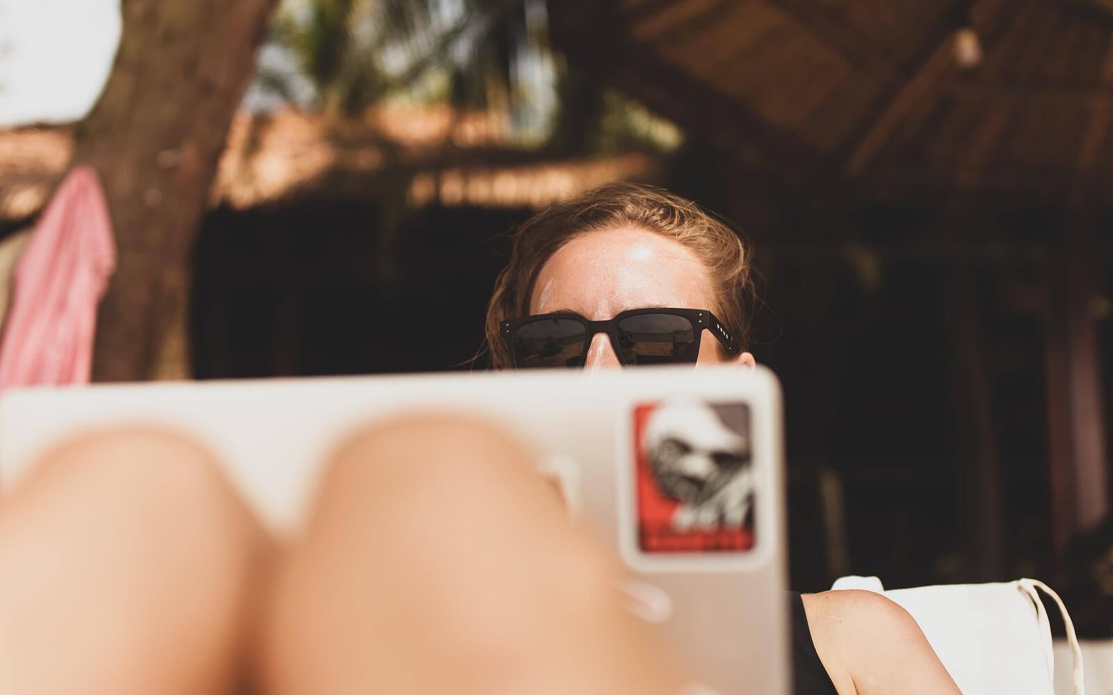 Woman in sunglasses relaxing with a laptop