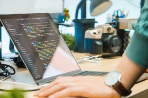 Remote IT jobs: A person stands in front of a laptop with code on the screen
