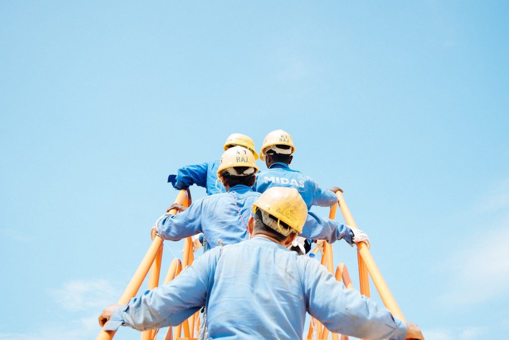 Independent contractors wearing hard hats while ascending a ladder