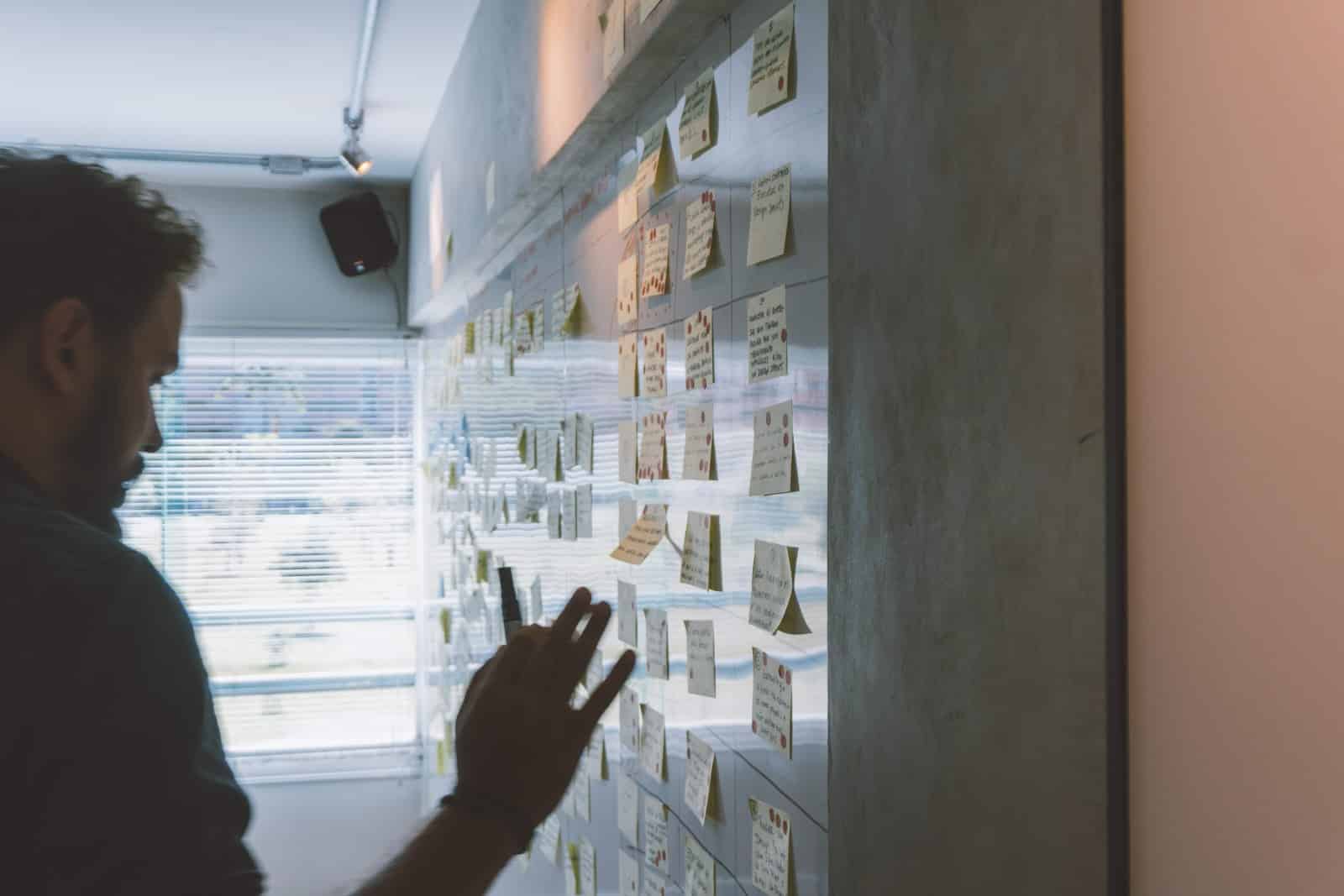 man stands by sticky notes on a wall