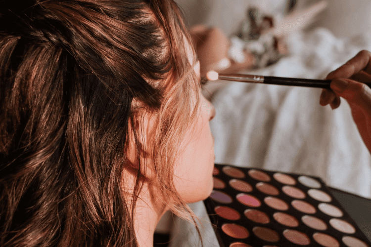 A close-up of a makeup artist applying makeup on a bride