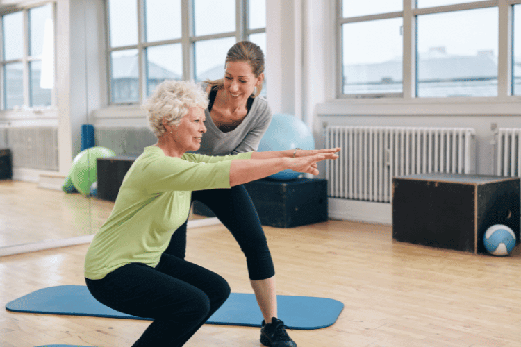 An elderly woman doing exercises with her personal-trainer at the gym 