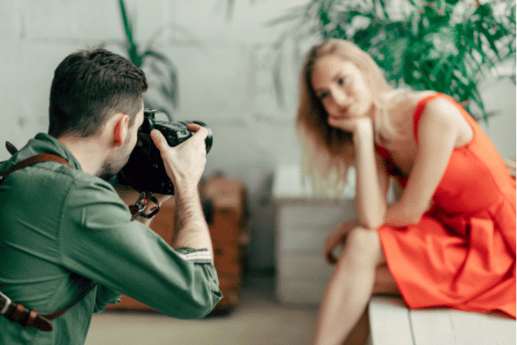 A male photographer taking professional photos of a model in a studio