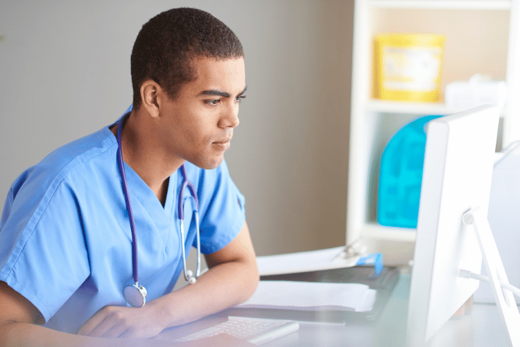 A male travel nurse working on a desktop computer