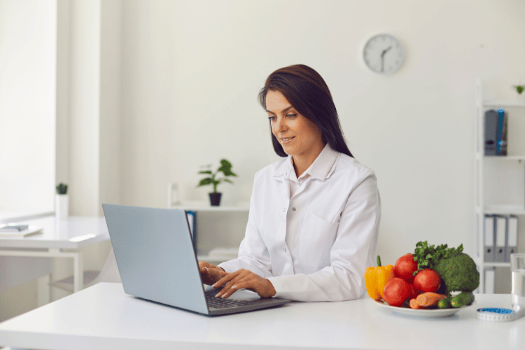 Young female dietitian typing in laptop keyboard in her clinic