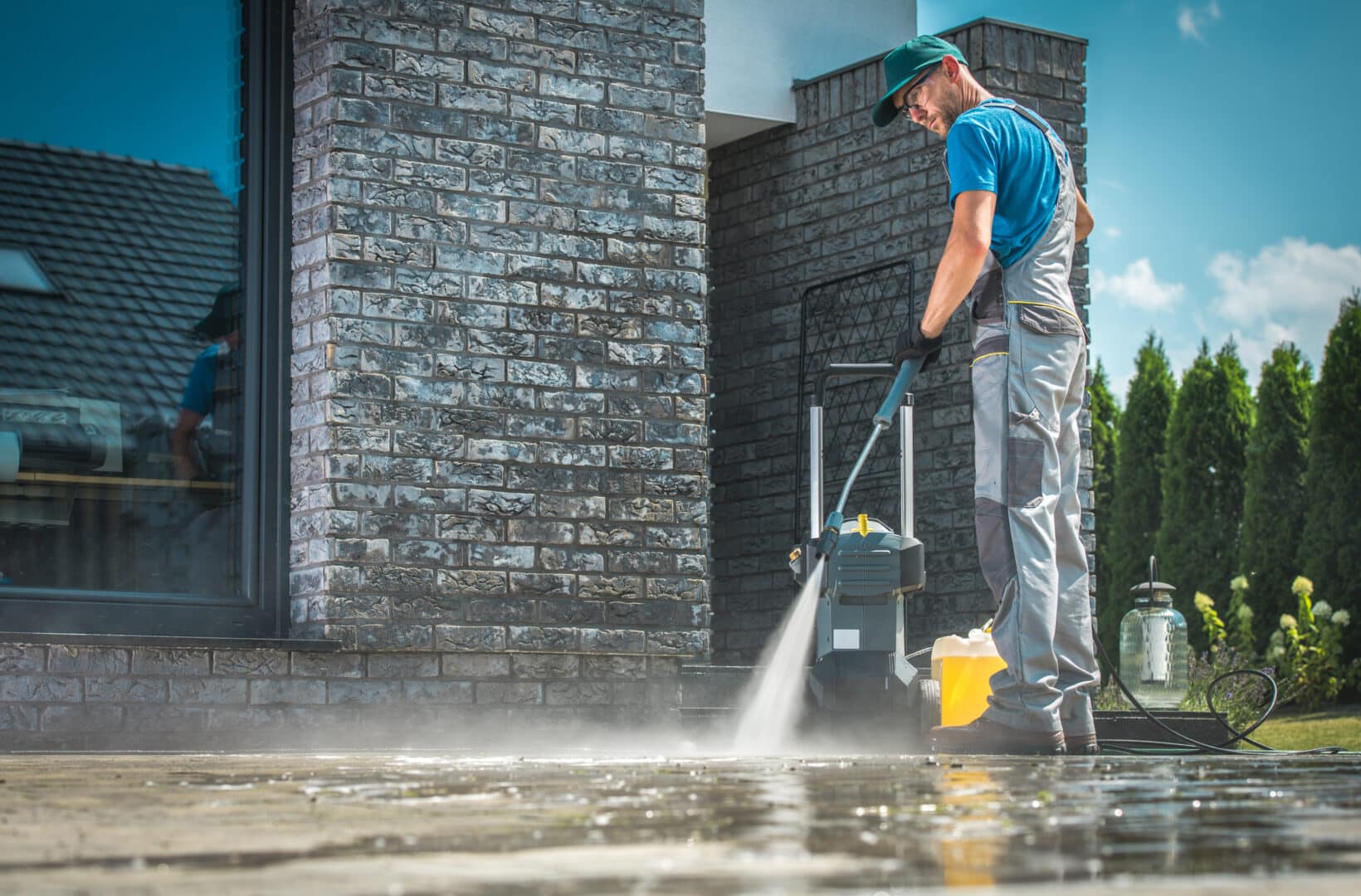 stock image showing a person standing outside of a business building, pressure washing the sidewalk - header graphic for a names for pressure washing business post on gigworker.com