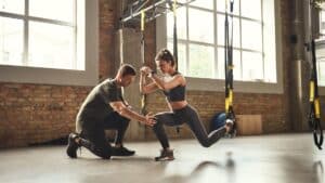 image showing two people in a gym, working on a TRX bar - for fitness business names post on gigworker.com